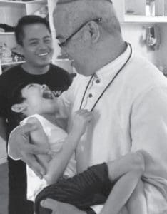 Bishop Alminaza cradles a disabled child